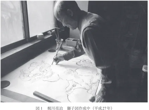 図 １  梶川亮治 獅子図作成中（平成27年） 度余裕のある方は、和風建築に、あのー、帰りつつあるよね。 うーん、そういう事はねえ、あのー、今、あのー、私らが、私なんか、もうあと数年 のことだからね。あのー、そういう形を見て、死ぬということはないと思うけど、そ ういうふうな傾向に行くということはねえ、間違いないんですよ。  ここで、鬼師、梶川亮治の受賞歴について簡単に述べておきたい。実は亮治自身も大き く変容を遂げているのであった。 2006 年 高浜市飾り瓦コンクール大賞受賞。 2007 年  碧南市市政