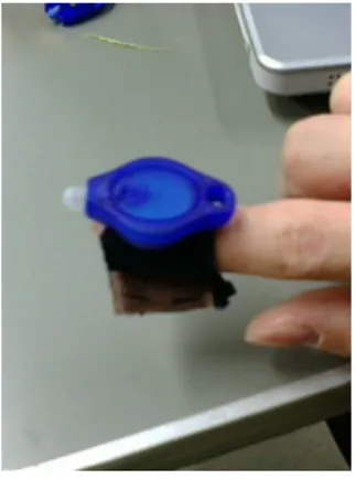 図 2.2: 作成した LED デバイス 図 2.3: 指先に装着した様子 たもので利き腕の人差し指に装着してもらう．本研究では，この指先につけた LED を利用し て手の認識を行っている．また，図 2.3 のように指一本のみに LED をつけてもらう形で非常 にシンプルであるので，デバイスを装着させることで利用者に与えてしまう拘束感などをか なり軽減できると思われる． なお，本研究で作成したシステムでは， LED デバイスを装着しなければ操作ができないよ うなものではなく，携帯電話のライトなどといった強い