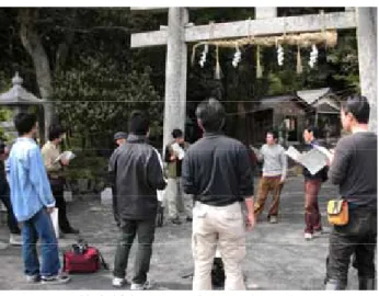 図 3-6  若宮神社前で，撮影の打ち合わせを行 う撮影班．  (2007 年 4 月 21 日，著者撮影)    ⑥松明祭本番に起こった事件    若宮神社内には各組から奉納された５本のドンガラ松明と，老人クラブより奉納されたホンガラ松 明の 6 本の松明が立てられていた．その内，ホンガラ松明は三番目に奉火されることになった．しか し，ホンガラ松明に奉火する前に，他の松明の火の粉がホンガラ松明に降りかかったのである．「消 防団水を持って来い！」「水をかけろ！」「あかん，はよ消せ！」「水はかけるな！」口々に