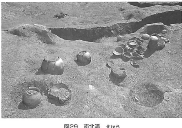図 ２ ８ 竪 穴 住 居 跡 Ａ 北 か ら この造成作業は、最終的には幅約1 5 ｍ以上の谷に、厚さｌ 〜1 . 5 ｍの上を入れるが、中央部は幅約５〜６ｍ、深さ５０ 〜7 0 ｃｍの溝とし、ここを廃棄物投棄場とする。東岸はl ﾘ ｊ 隙だが、西岸については緩傾斜･ で、工房作業而に到る。ま た、調査区北端付近から下流は、谷中央を造成土上から 深く棚り込んで水溜を作り、廃棄物の投棄場としている。 後述のように、造成土のI ￨ ､ １局にあたる茶褐色上上面でも、 西岸で方形の大型炉を検出しており、造成が進
