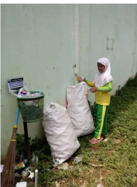 Gambar 9 Seorang siswi yang sedang memisahkan sampah botol  plastik (anorganik). 