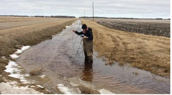 Figure 6. Stream sampling at Pelican Lake during March spring melt runoff.