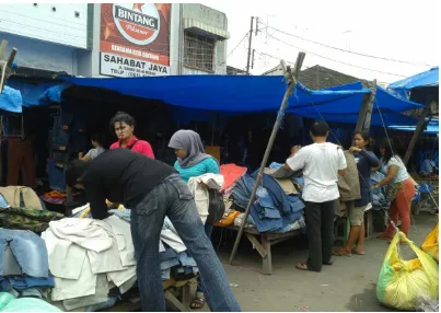 Gambar 3: Juni Hom berpose disalah satu tempat yang menjual pakaian bekas. Disaat itu seorang pembeli yang tidak jadi membeli pakaian bekas yang diinginkannya dan pergi berlalu sambil bercerita kepada temannya