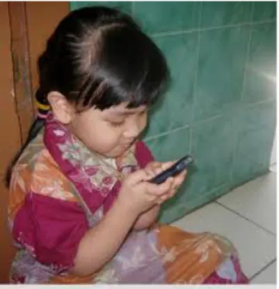 Gambar II.14 Anak yang bermain dengan game handphone. 