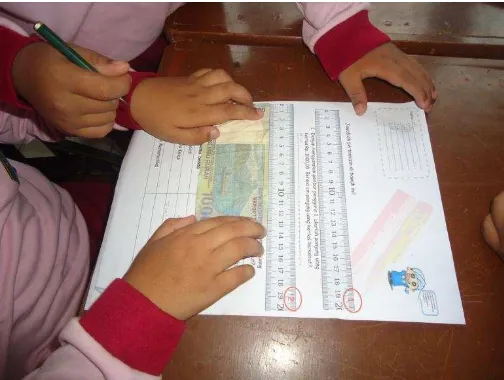 Gambar 5. Siswa mengukur panjang uang kertas seribuan dengan `menggunakan dua jenis penggaris 