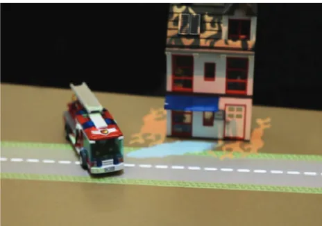 Figure 12. The LEGO Oasis demo using RGB-D recognition [21]. Near-real-time object recognition allows interesting human–computer interactions using an overhead projector: a LEGO fire truck putting out a virtual fire on a house.