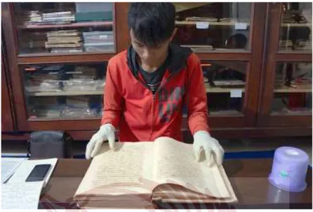 Gambar  3.  Agar  buku  tidak  sobek  atau  rusak,  setiap  pengunjung  diwajibkan  memakai  kaus  tangan  saat  membaca  buku  kuno  di  Perpustakaan Museum Radya Pustaka