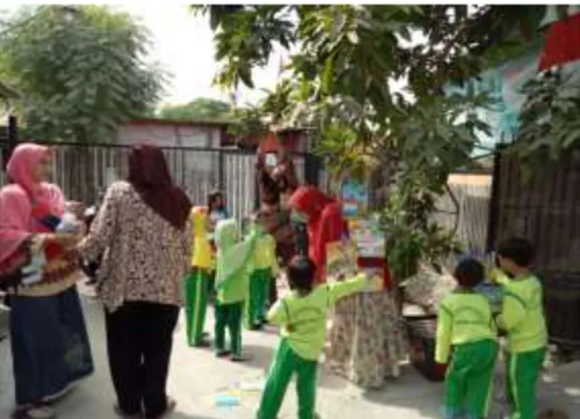 Gambar 3. Anak-anak menggantungkan buku-buku di  pohon bersama guru 