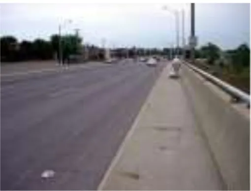 Figure 1: A lone pedestrian wheeling his groceries through a dreary, car-dominated landscape on Keele Street over Highway 401 in Toronto, Ontario 