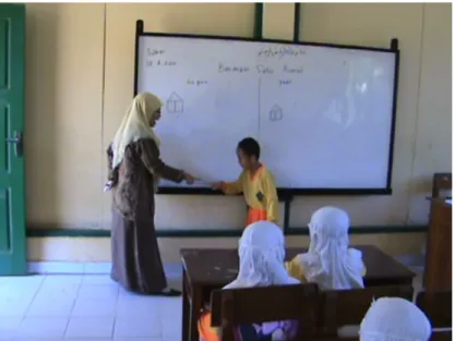 Gambar 15. Guru mendemonstrasikan bermain satu rumah bersama seorang siswa  Guru  : Kita buat rumah dulu, rumah besar atau rumah kecil 