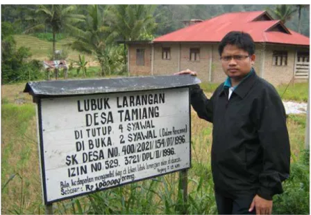 Gambar 1.  Penulis berfoto di dekat papan pengumuman Lubuk Larangan Desa Tamiang.