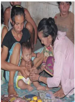 Gambar 2.5 Ritual Palas Bidan. Gambar diatas Bidan kampung terlihat  sedang memasang ongui kepada bayi yang dulu telah ditolongnya 