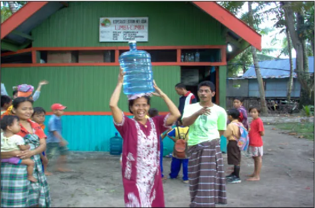 Foto 6 : Penduduk membawa air hasil olahan air siap minum dalam botol galon. 