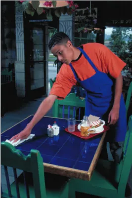 Figure 1.25:  A buser clears and  cleans tables and sets up tables for  the next customers.