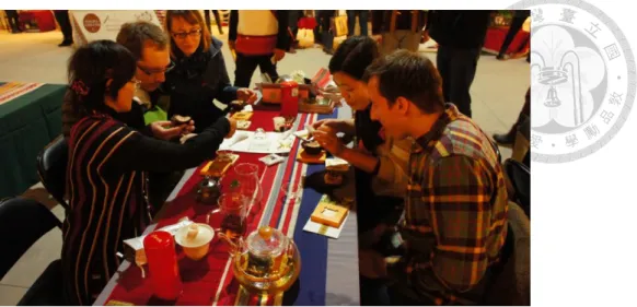 圖  5 在原住民觀光元年成果展會場中，原住民茶農與外國觀光客的茶席互動                      圖片來源：本研究自行拍攝          這個差異正好回應了我第一次在田野中的觀察。在第一年參展的時候，喬伊 姊很幸運地受邀到原住民觀光成果展賣茶，但她也對主辦單位的要求感到不知所 措，「主辦單位還要求我要穿上傳統服飾，對呀，我是原住民，為什麼他們還要 求我穿上原住民的服飾呢？」她說。然而，實際上到了會場，很明顯地觀察到大 多數的工作人員幾乎都穿上了傳統服飾，言行舉止悠遊自若，但是，在原住民